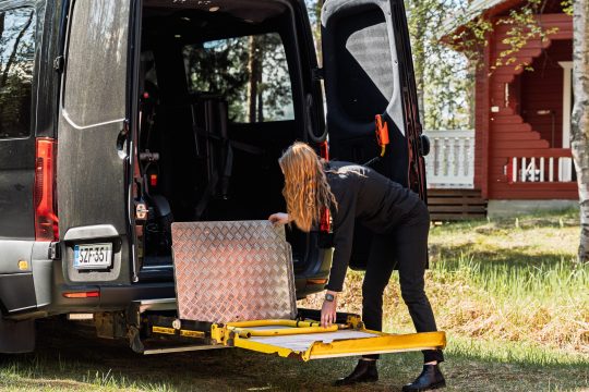 Kuljettaja laskee pyörätuolinostimen esteettömän taksin takaovesta